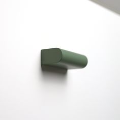 the corner of a white table with a green object on it's side and a black object in the middle