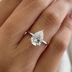 a woman's engagement ring with a pear shaped diamond