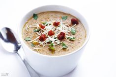 a white bowl filled with soup next to a spoon