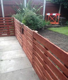 a wooden fence in the middle of a yard with plants growing on top of it