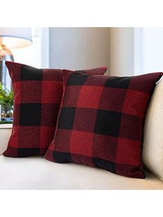 two red and black plaid pillows on a white couch