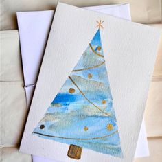 two christmas cards with watercolors on them, one blue and the other white