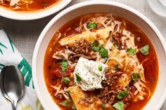 two bowls of pasta soup with meat, cheese and parmesan bread on the side