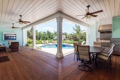 an outdoor kitchen and dining area with pool in the background