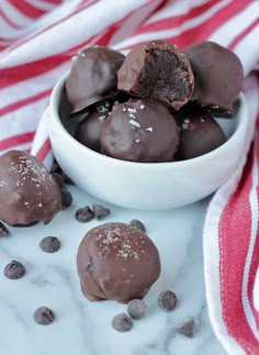 a bowl filled with chocolate truffles on top of a white plate next to a red and white towel