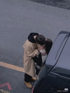 a man and woman kissing in front of a car