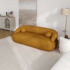 a yellow couch sitting on top of a white rug in a living room next to a lamp