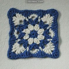 a crocheted square with white and blue flowers on it