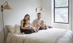 a man and two women sitting on top of a bed with three children in front of them