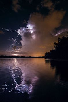 the sky is filled with lightning as it shines through the dark clouds over water