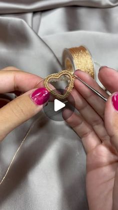 a woman with pink nails is working on some beads and thread in her hands,