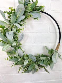 a wreath with green leaves hanging on a brick wall