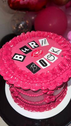 a pink cake with numbers on it sitting on top of a black and white plate