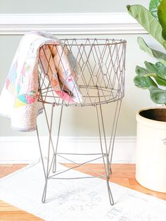 a potted plant sitting next to a wire basket on top of a wooden floor