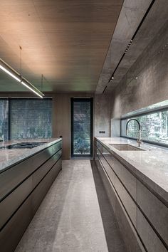 an empty kitchen with marble counter tops and stainless steel appliances on the counters in front of large windows