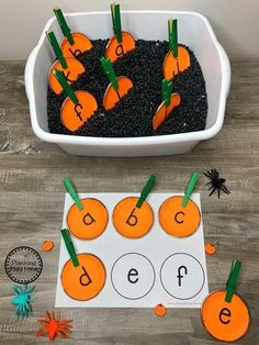 a bowl filled with dirt and carrots on top of a wooden table next to cut out letters