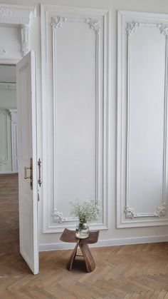 a vase with flowers sitting on top of a table in front of two white doors