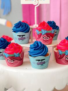 cupcakes with blue frosting and pink icing on a white cake stand