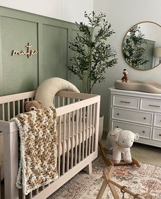 a baby's room with a crib, dressers and a tree in the corner