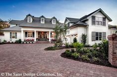 a white house with brick driveway and landscaping