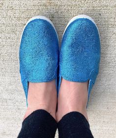 a person wearing blue slippers standing on top of a carpeted floor with their feet in the air