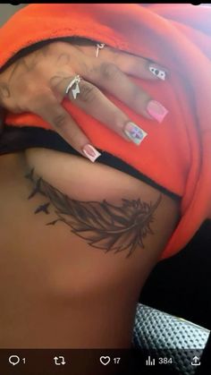 a woman's stomach with tattoos on it and an orange hoodie over her