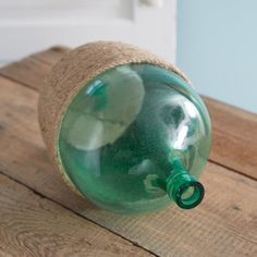 a green glass bottle sitting on top of a wooden table