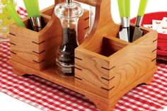 an assortment of kitchen utensils in wooden containers on a checkered tablecloth