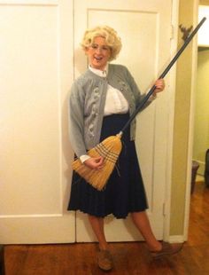 a woman standing in front of a door holding a broom