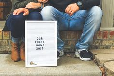 two people sitting on the steps with a sign that says our first home is 2017