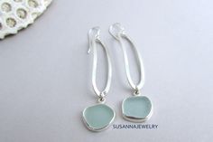 Find a gift she'll cherish. Timeless jewelry for every occasion. Our sterling silver and sea glass dangle earrings feature a long, slender modern design. OOAK pieces of surf tumbled sea glass are first chosen to coordinate, then carefully wrapped in fine silver bezel wire with an eye-catching polish. Each lengthy oval of sterling wire is shaped and hammered by artisan Susan Volger. There is a lot of movement in these earrings and they are very comfortable to wear. They dangle from a pair of ster Elegant Jewelry With Sea Glass And Ear Wire, Elegant Sea Glass Jewelry With Ear Wire, Elegant Sea Glass Dangle Earrings, Elegant Silver Sea Glass Earrings, Beach Earrings In Silver With Recycled Glass, Beach Silver Earrings With Recycled Glass, Silver Recycled Glass Beach Earrings, Silver Recycled Glass Earrings For The Beach, Silver Sea Glass Earrings For Beach