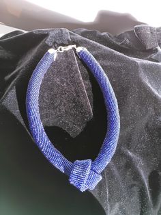 a blue necklace sitting on top of a black bag with a silver clasp around it