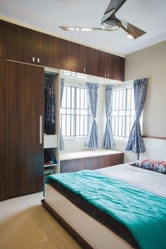 a bed sitting under a window next to a wooden dresser and closet in a bedroom