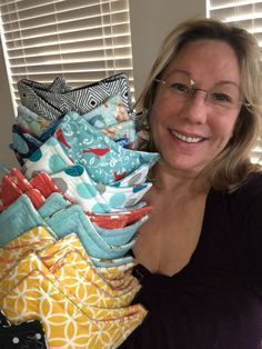 a woman with glasses holding a stack of cloths