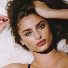 a close up of a person laying on a bed with her hair blowing in the wind