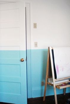 a painting easel in front of a blue and white wall next to a door