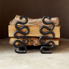 two black metal snakes sitting on top of a piece of wood