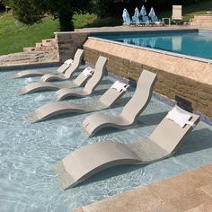 four lounge chairs sitting in the middle of a swimming pool