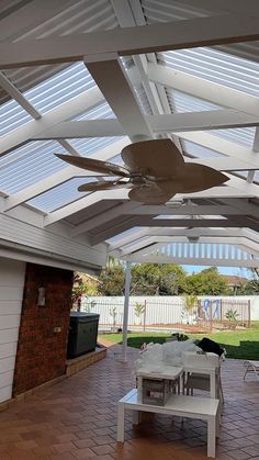 a covered patio area with a table and ceiling fan