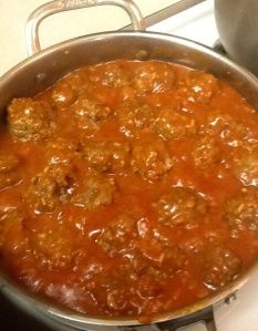 a pot filled with meatballs and sauce on top of a stove