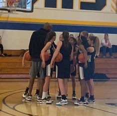 the girls basketball team huddles together on the court for a timeout before their game