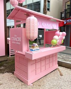 a pink ice cream stand with lots of desserts on it's display table