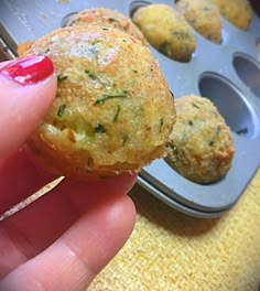 a person holding up a muffin in front of some muffin tins