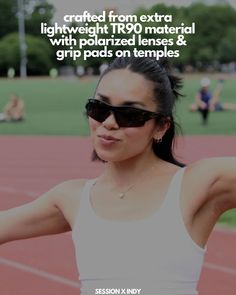 a woman wearing sunglasses and holding her arm out in front of the camera on a track