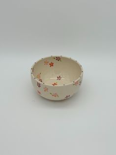 a small bowl with flowers painted on the side and bottom, sitting on a white surface