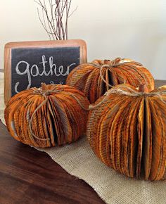 three small pumpkins sitting on top of a table next to a chalkboard sign