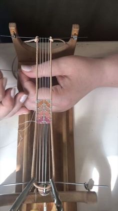 two hands are working on an instrument with strings attached to the neck and bottom of it