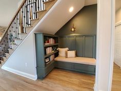 a room that has some bookshelves under the stairs and a bench in front of it