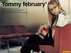 a woman sitting on a red chair in front of a wall with a magazine cover