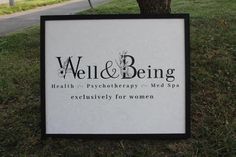 a sign for well and being on the side of the road in front of a tree